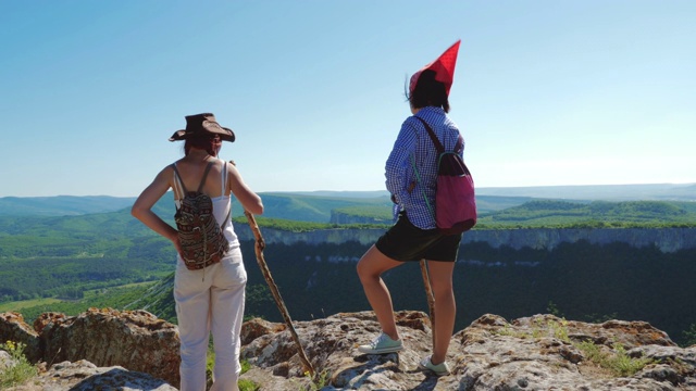 两个女孩旅行者女友走在一个高山高原上，欣赏惊人的景色。视频素材