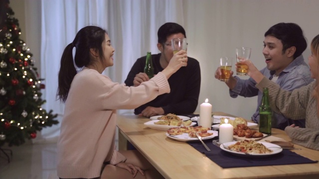 一群亚洲朋友在圣诞晚宴上欢声笑语。快乐的泰国人一起吃披萨在派对期间在家。慢动作的场景视频素材
