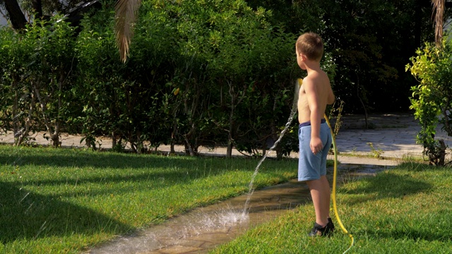 孩子在用软管浇草坪时玩得很开心视频下载