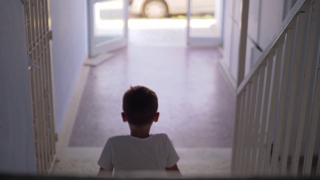 一个孩子独自坐在楼梯上视频素材