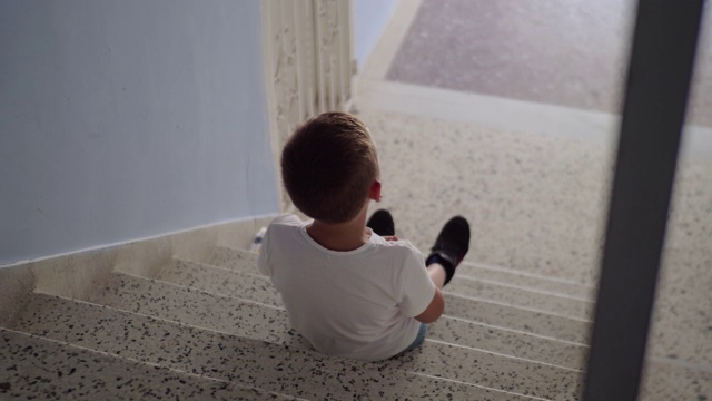 被冒犯的孩子坐在楼梯上视频素材