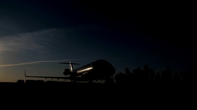 傍晚，乘客的剪影接近准备降落的飞机。视频素材