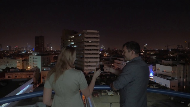一名男子和一名女子在以色列一家旅馆的屋顶上注视着特拉维夫的夜晚视频下载