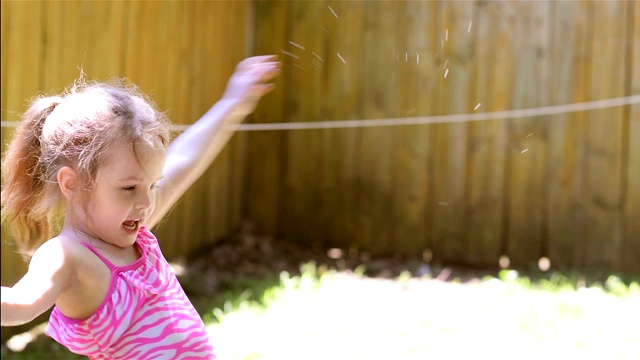 夏天，一个小女孩在后院玩水管视频素材