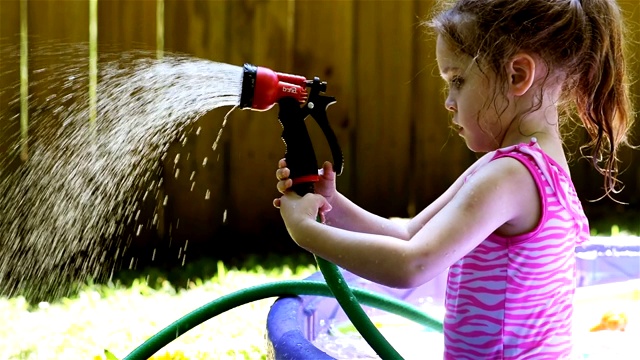 小女孩在后院的游泳池里玩洒水器视频素材