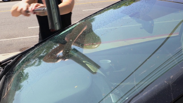 一个女人正在用加油站的橡皮擦清洗汽车挡风玻璃视频下载
