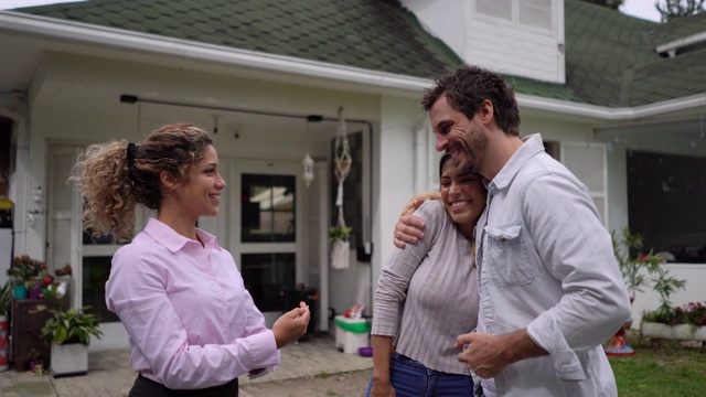 一对幸福的夫妇在接受钥匙时微笑着与一处房产的女经纪人达成了一笔交易视频下载
