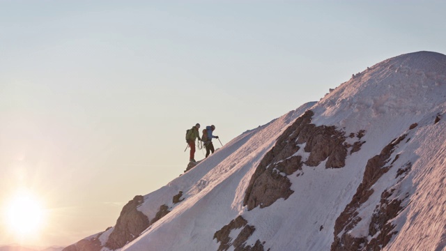 男性登山运动员在白雪覆盖的山脊上行走视频下载