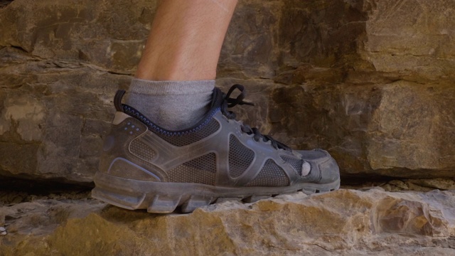 攀登者脚上的徒步靴攀登岩石山时，旅行。男人们穿着登山鞋爬上悬崖。旅游和旅游概念。视频素材