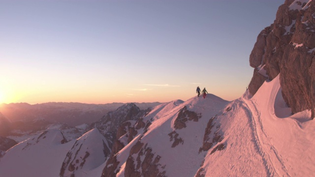 日出时分，人们在白雪覆盖的山脊上行走视频素材