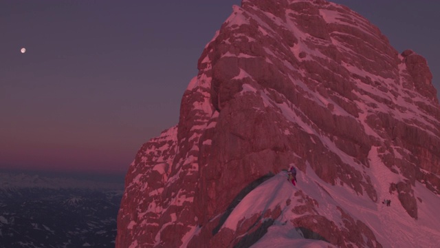 雄鸟在日出时在白雪覆盖的山脊上徒步视频素材