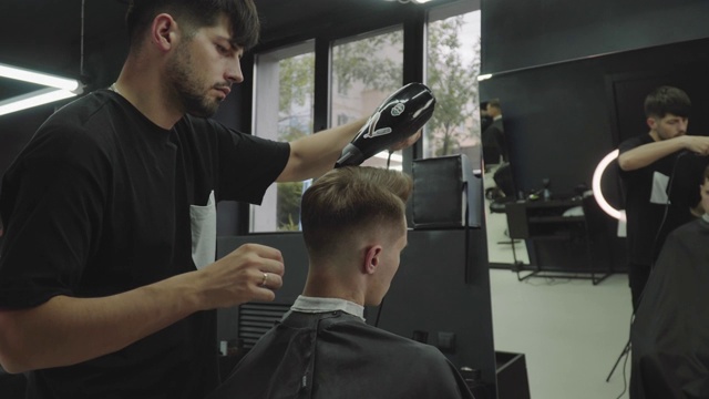 男性用电动剃须刀理发。理发师在理发店用理发器为顾客理发。男人用电动剃须刀理发。手持拍摄的。4 k视频素材