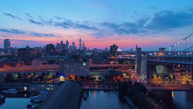 照明费城市中心，本杰明富兰克林桥和码头在老城在特拉华河晚上。无人机视频与全景和上升相机运动。视频下载