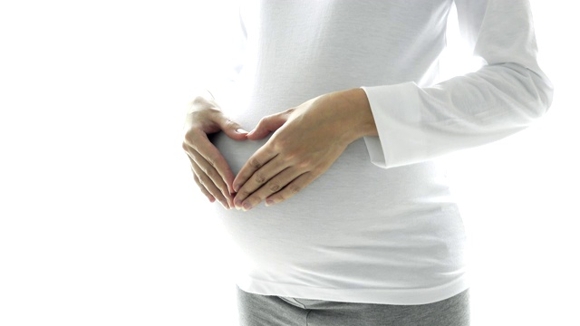 美丽的孕妇的近距离拥抱她的肚子与心脏形状的手视频素材