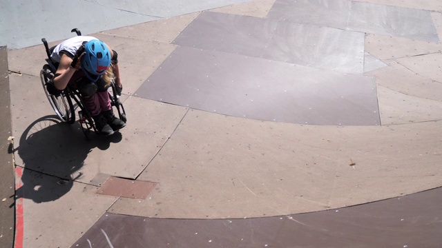 滑板公园里坐轮椅的女子摔倒后站起来视频下载