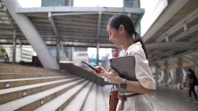 亚洲女人走路用电话语音识别在城市视频下载