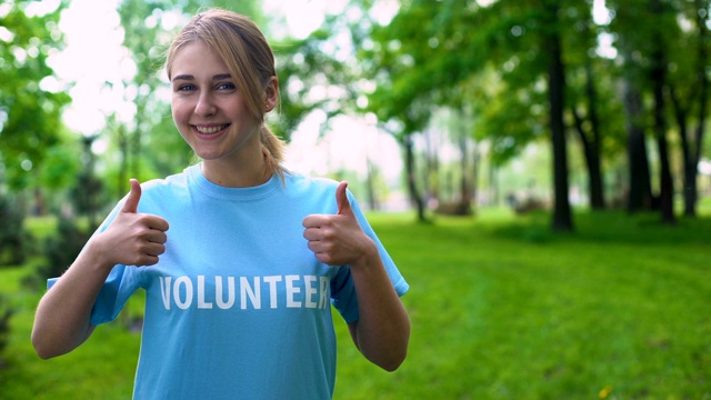 快乐的女志愿者竖起大拇指站在森林里，自然资源视频下载