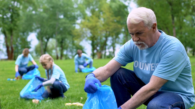 老年志愿者收集塑料垃圾放入垃圾袋，环保活动视频下载