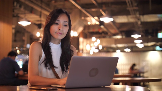 亚洲妇女在休闲服装使用笔记本电脑为她的工作视频下载