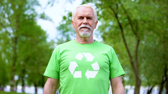 老人穿着印有回收标志的t恤看着相机，背景是森林视频下载