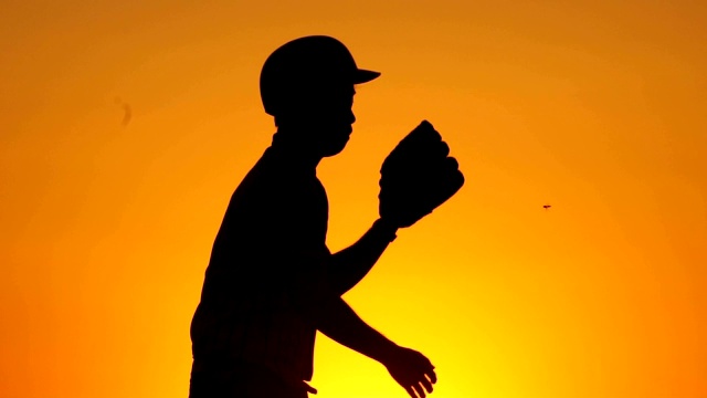 一个戴着棒球手套的剪影男人正在接棒球视频素材