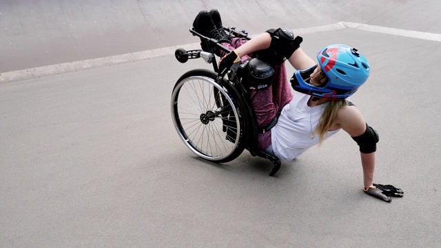 坐在轮椅上的残疾妇女在滑板公园表演特技视频下载