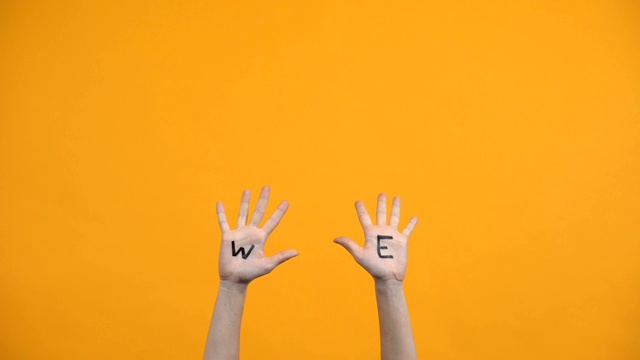 我们把手掌写在橙色的背景上，志愿者举起手，团结在一起视频素材