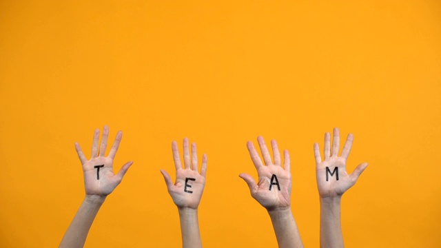 团队手掌心写在橙色背景上，团结合作，团队团结视频素材
