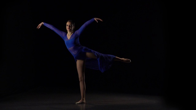 性感的芭蕾舞演员在工作室的黑色背景下跳舞。慢动作视频下载