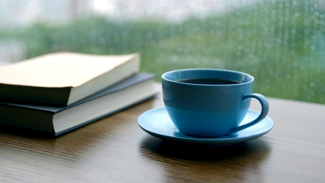 书和咖啡杯放在下雨天的木桌上视频素材