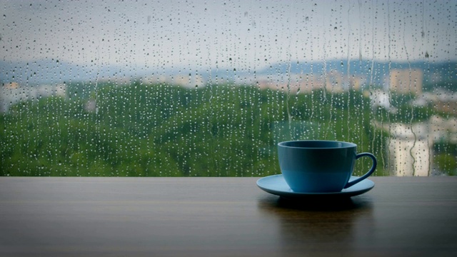 咖啡杯放在木桌上，背景是雨滴视频下载