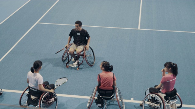 中镜头的年轻女性轮椅网球运动员一起练习与他们的教练视频下载