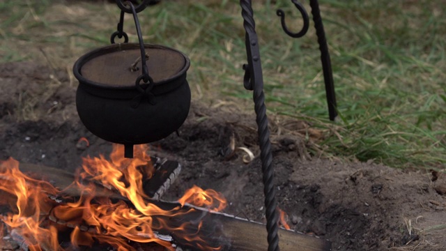 营地外面的火堆上的黑色金属烹饪锅。在营火上准备食物视频素材