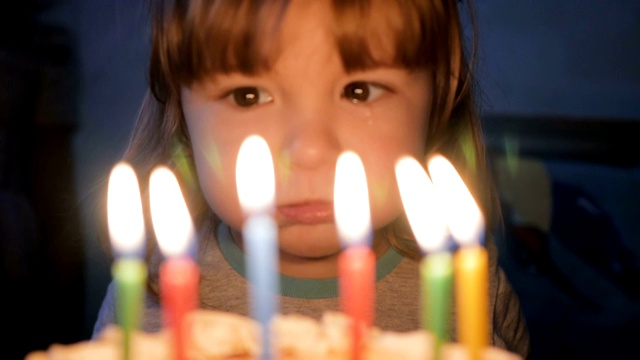 小男孩吹灭生日蛋糕上的蜡烛。特写镜头。缓慢的运动。视频素材