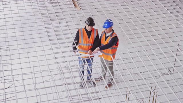 CS男建筑师和工头在正在施工的工业大楼的一楼交谈视频下载