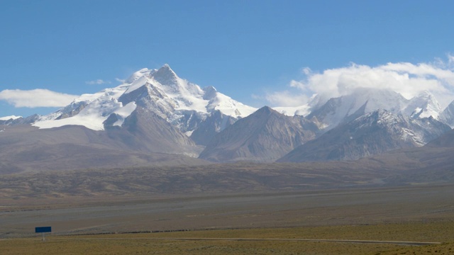 广阔的岩石平原通向阳光灿烂的西藏雄伟的雪山视频素材