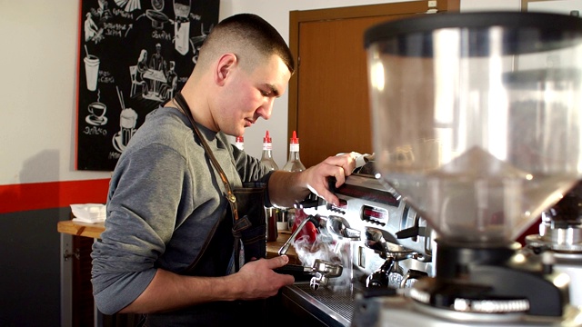 一个年轻男性咖啡师使用专业咖啡机工作的肖像视频下载
