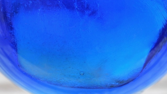 在玻璃杯中与冰块发生反应的蓝橙色甜酒视频下载