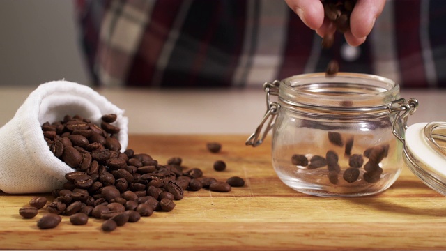 男子将烤好的咖啡豆从手扔进近4K白色袋子的罐子里视频下载