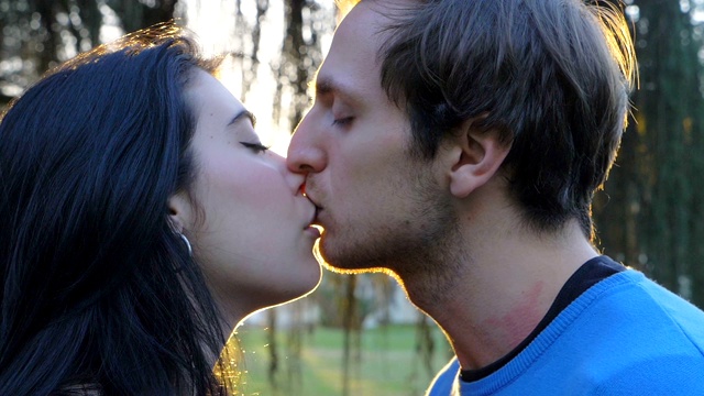 浪漫、欲望、爱情。一对年轻的情侣在日落公园的慢动作接吻视频下载