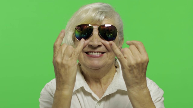 一位上了年纪的妇女用手画着犄角。色度键视频下载