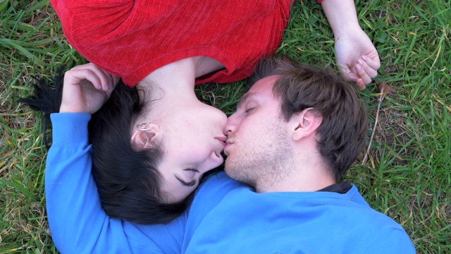 浪漫的年轻情侣躺在草地上接吻。爱情,浪漫,吸引力视频下载