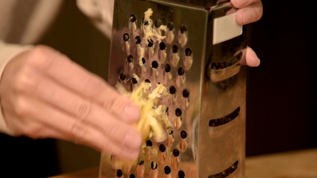 特写女子的手在金属磨碎器上擦干净的生姜根。视频素材