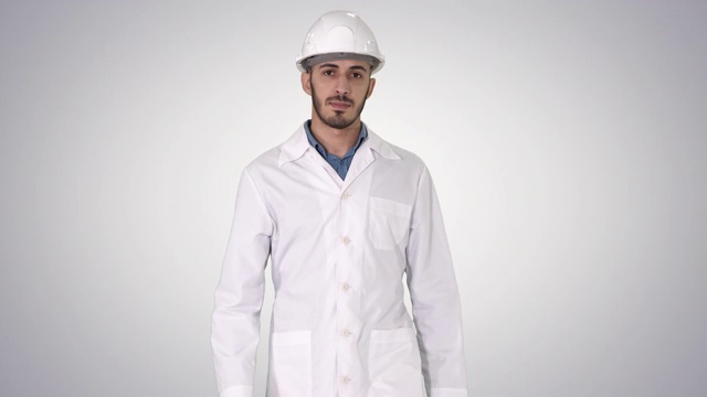 阿拉伯工程师戴着头盔，身穿白袍，在渐变背景上向前走视频下载