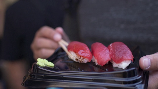 亚洲背包客游客在日本街头小吃市场吃金枪鱼寿司视频素材