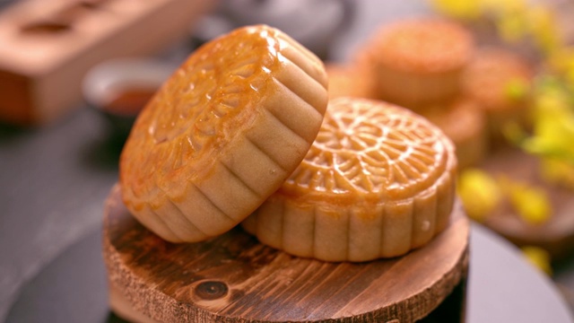 美丽的月饼在木托盘旋转，茶和花在黑石板背景。中国传统中秋节概念视频。视频素材