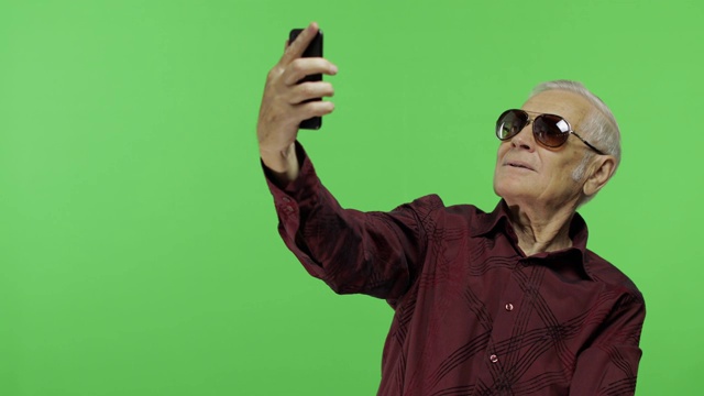 一位戴着墨镜的老游客用智能手机拍了一张照片。有问题视频下载