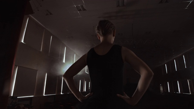 慢动作:首席芭蕾舞演员穿着黑色礼服，表演旋转和优美的舞蹈动作。摄像机在万向节上移动。视频素材
