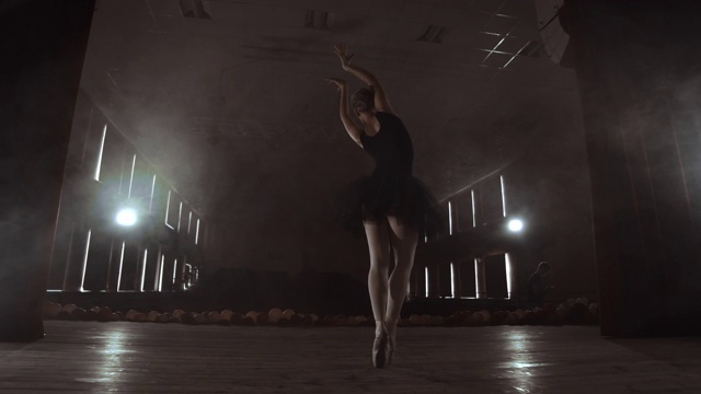 慢动作:芭蕾舞团在黑色的裙子上表演旋转和舞蹈优美的动作排练一个独奏节目。摄像机在万向节上移动视频下载