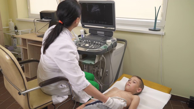 女儿科医生操作超声波扫描仪检查她的年轻病人的腹部。视频素材